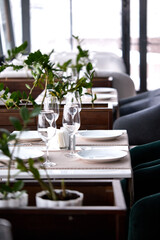 Wineglasses and white plates in restaurant on on table, part of the interior