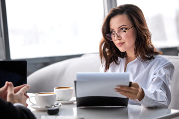 serious and confident business lady in formal shirt and eyeglasses talking with business partner