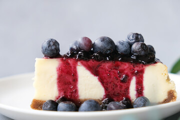 Slice of cheesecake with blueberry jam and fresh berries on plate. Sweet delicious homemade cake closeup.