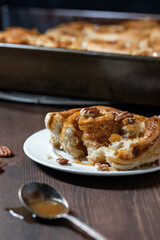 Close up of a cinnamon bun torn open and topped with caramel sauce and pecan nuts.