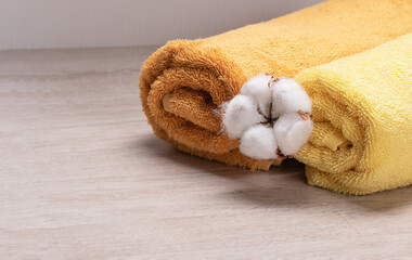 yellow bath towels on a light background with cotton flower. Spa concept 