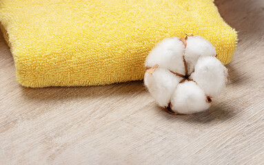 yellow bath towels on a light background with cotton flower. Spa concept 