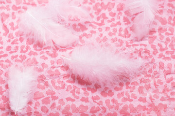 delicate pink background with fluffy white feathers on decor paper.Romantic background for a greeting card.