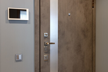 Shabby design entrance door in a modern apartment hallway, video intercom device on the wall. Neutral tones. Security concept, trendy interior. Horizontal