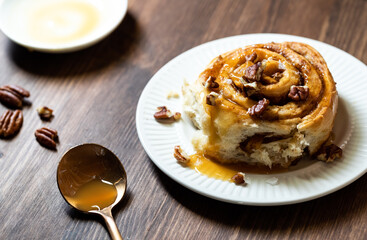 Close up of a homemade cinnamon swirl topped with caramel sauce and pecan pieces taken from above.