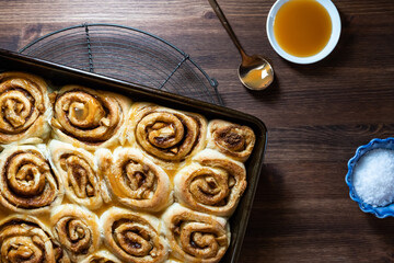 Top down view of cinnamon buns in a pan with caramel sauce and course salt.