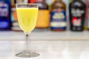 Egg liqueur in shot glass prepared by the bartender on the background of bottles in the bar