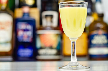 Egg liqueur in shot glass prepared by the bartender on the background of bottles in the bar