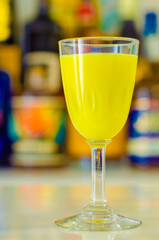 Egg liqueur in shot glass prepared by the bartender on the background of bottles in the bar
