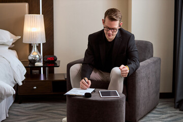Caucasian man in elegant suit writing notes, working in room