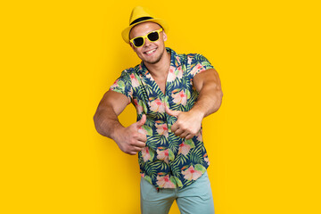 Young sportve man on vacation wearing floral summer shirt over yellow background success sign doing...