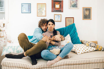 Young couple watching tv and eating popcorn