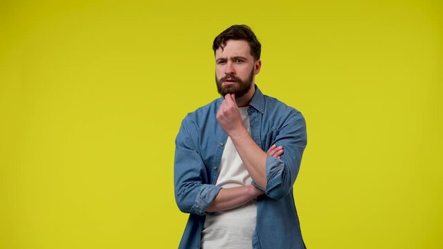 Portrait of a man, thinking intently, putting his hand on his chin, happily raising his index finger, an idea arose. A man in the studio on a yellow background. Close up. Slow motion ready 59.97fps.