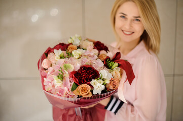 excellent bouquet of white, pink and red flowers in hands of smiling blonde woman