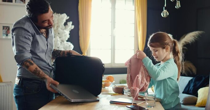 Man Is Talking On The Phone And Packing His Laptop, Getting Ready To Go To Work. The Girl Is Packing Books In Her Backpack, Getting Ready To Go To School. Dad And Daughter, Morning Family Routine 