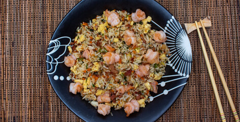 Yakimeshi is rice and eggs, shrimp, vegetables and more in the black plate. Asian food.