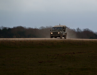 Fototapeta premium british army land rover defender 4x4 speeds along a dusty stone track 