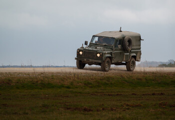 british army land rover defender 4x4 speeds along a dusty stone track on a military exercise, Salisbury Plain UK