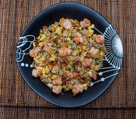Yakimeshi is rice and eggs, shrimp, vegetables and more in the black plate. Asian food.