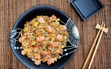 Yakimeshi is rice and eggs, shrimp, vegetables and more in the black plate. Asian food.