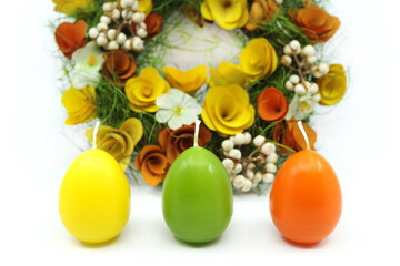 Easter wreath decorated with flowers on white background. Colourful Easter candles. Easter concept. 