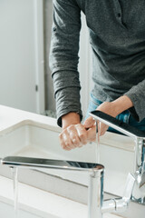 A man washes his hands in the bathroom according to COVID-19 cleaning protocol. Reducing the spread. Hygiene 