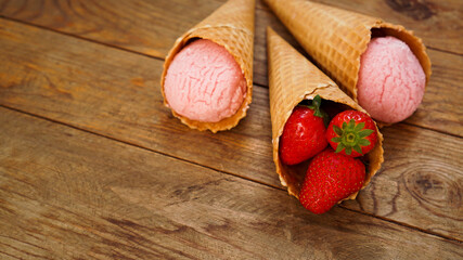 Strawberry ice cream in a waffle cone. Red berries and ice cream balls
