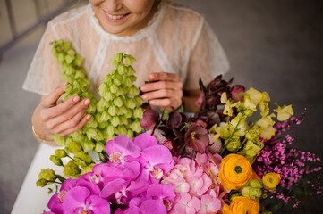 close-up of different fresh flowers in large bouquet and smiling woman florist nearby