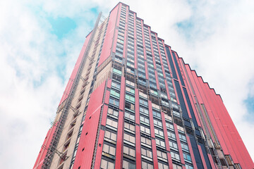 The facade of a red residential skyscraper under construction against the sky.