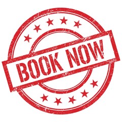BOOK NOW text written on red vintage stamp.