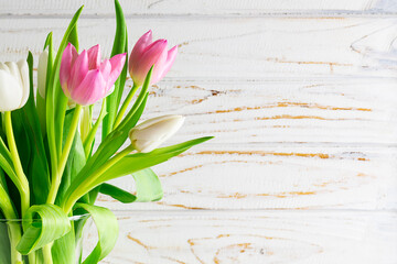 Beautiful tulip flowers in a vase on white rustic background with copy space for your design. Spring greeting card template.