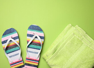 pair of female beach slippers and a green towel on a green background