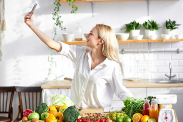happy female diettian with smartphone in hands in kitchen