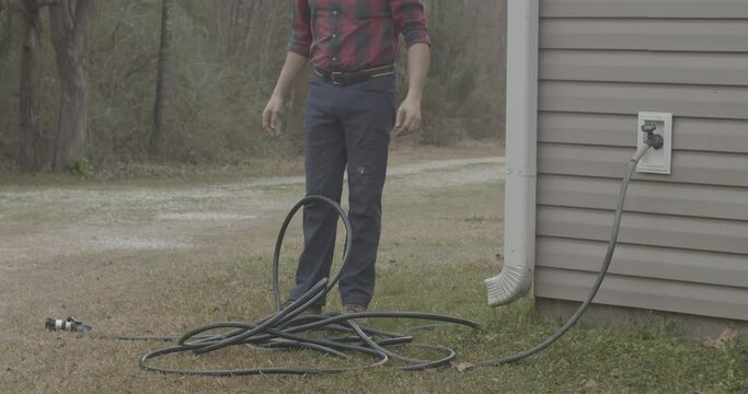 Male throwing a tangled garden hose on the ground in frustration.