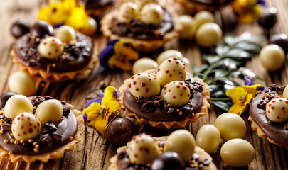 Close up view of an Easter mini tart with chocolate Easter eggs on a wooden table. Delicious easter dessert.