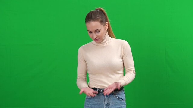 Portrait of young Caucasian woman smelling unpleasant smell on green screen. Slim beautiful lady making dissatisfied facial expression standing on chromakey background.