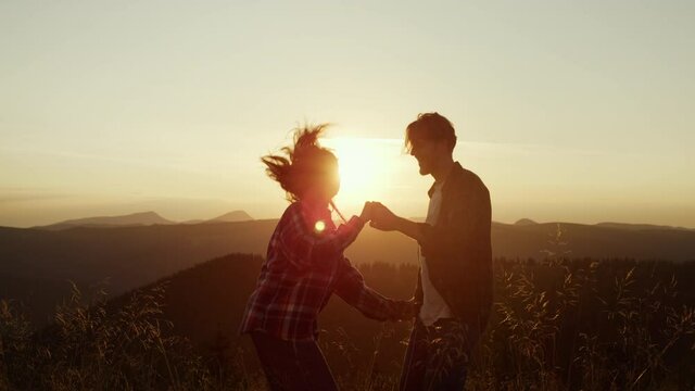 Woman and man dancing on top of mountain. Couple making funny moves during dance