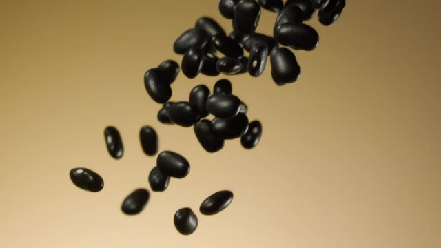 Beautiful black kidney beans falling in slow motion over a brown background