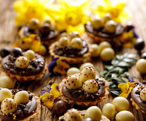 Easter chocolate mini tarts decorated chocolate Easter eggs, focus on the tart inside, close-up. Easter delicious dessert.