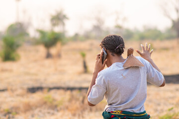 female african farmer making a phone call, back view