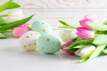 Beautiful Easter card with traditional eggs and fresh tulips on white wooden background. Happy Easter background.