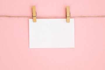 Rope with empty white paper frames with space for copy and clothespins on a pink background