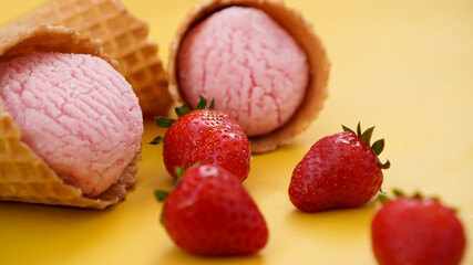 Strawberry ice cream in a waffle cone. Ice cream and berries on a yellow
