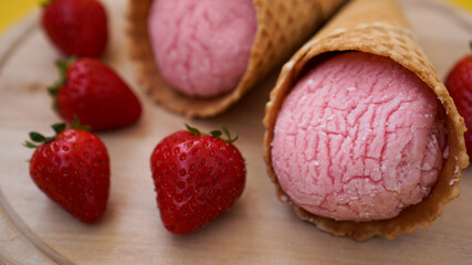 Strawberry ice cream in a waffle cone. Red berries and ice cream balls