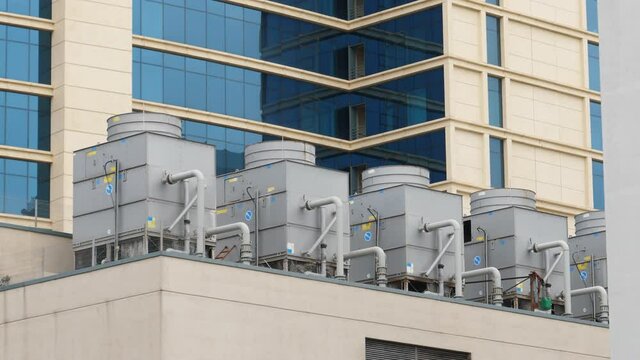 Horizontal 4k footage of of Six large AC air conditioning HVAC unit on the rooftop of modern hotel business-center skyscraper building
