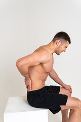 Obraz premium A man sits back pain keeps his hand on his back painful, cramp spine isolated stress, human Tension care, back suffer attractive