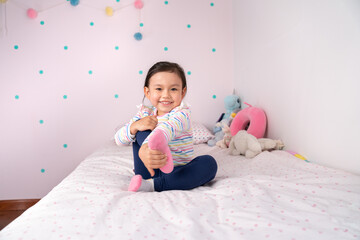 Portrait of a little girl exercising on the bed..