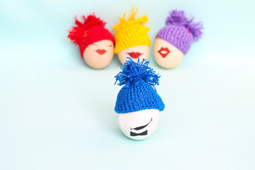 Easter eggs with faces in colorful knitted hats