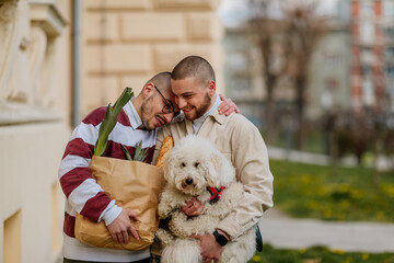 Gay couple walking home after grocery shopping with dog