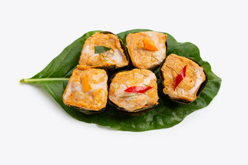 Thai streamed fish curry in banana leaves on white.